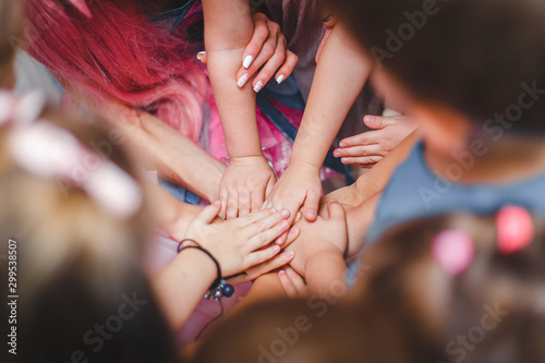 team play work. children hold joined clasped hands together. Kidk keep hold your hands together. Play in kindergarten. Group of children putting their hands together
