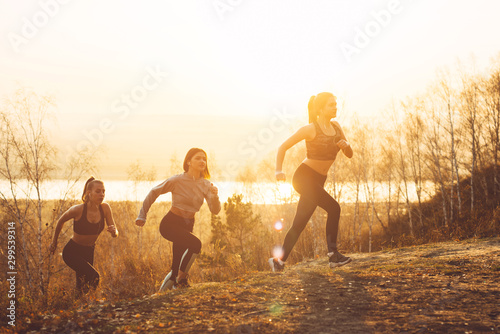 Several girls in sportswear are jogging outdoors in the sun.