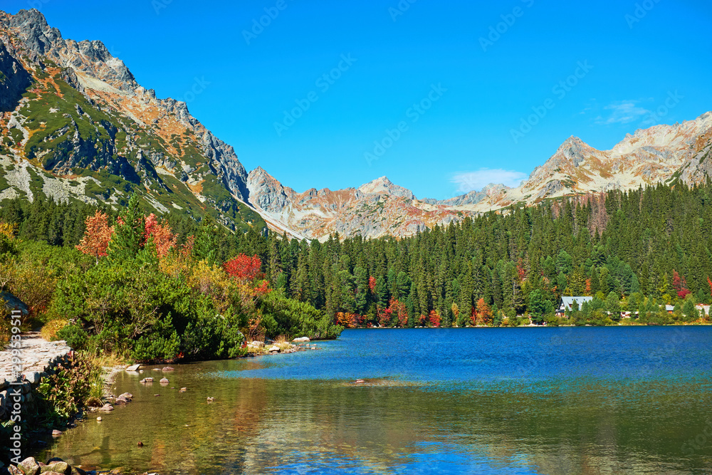 The autumn Poprad lake with mountain peaks and colorful forests near in High Tatras National Park, Slovakia