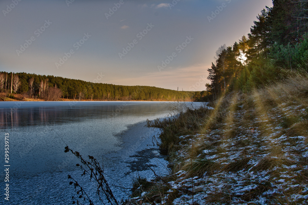 landscape sunset in the woods. winter pine forest on the banks of the frozen river.