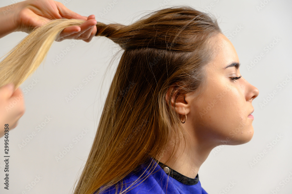 Fototapeta premium Studio photo of the work of a makeup artist by a hairdresser beautician. Creating beautiful makeup and hairstyles, rejuvenating the skin of the face. The professional is working with special tools.