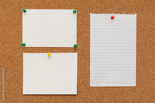Note paper swith push pins on cork board. Empty paper pages for notes copy space