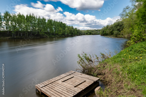 summer riverscape with blue sky, clouds and water reflections