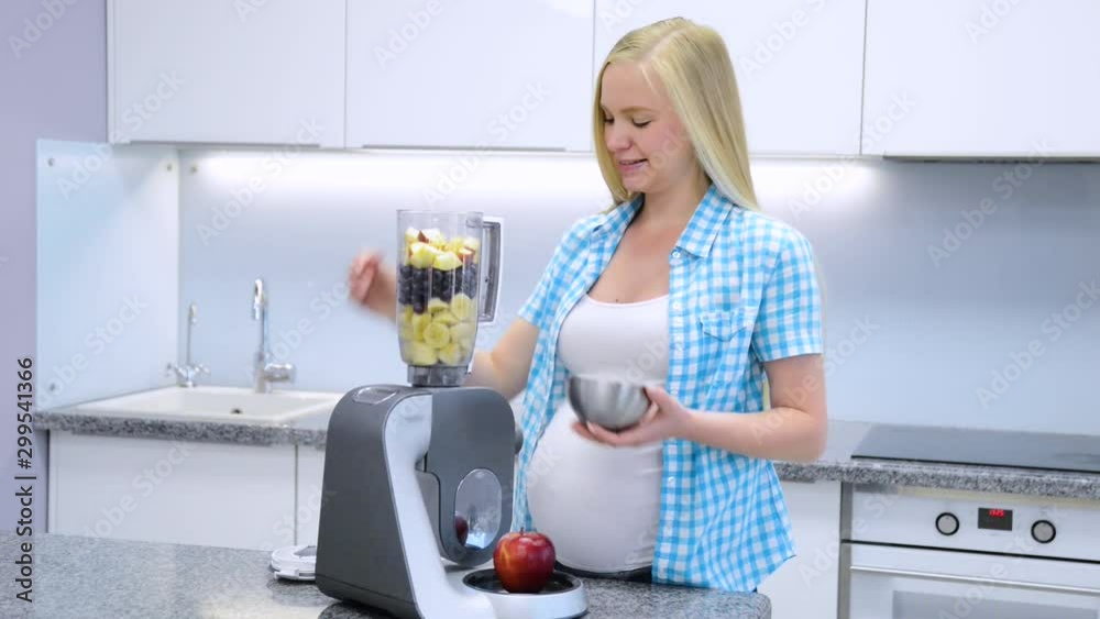 Portrait of a smiling pregnant woman cooking in her kitchen Portrait of a smiling pregnant woman cooking in her kitchen