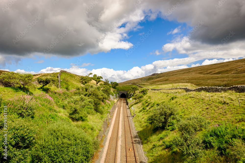 Beautiful, idyllic view of part of the famous railway track seen in the heart of the Dales. Taken from a stone bridge, a railway tunnel is visible.