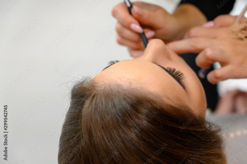 Obraz premium Studio photo of the work of a makeup artist by a hairdresser beautician. Creating beautiful makeup and hairstyles, rejuvenating the skin of the face. The professional is working with special tools.