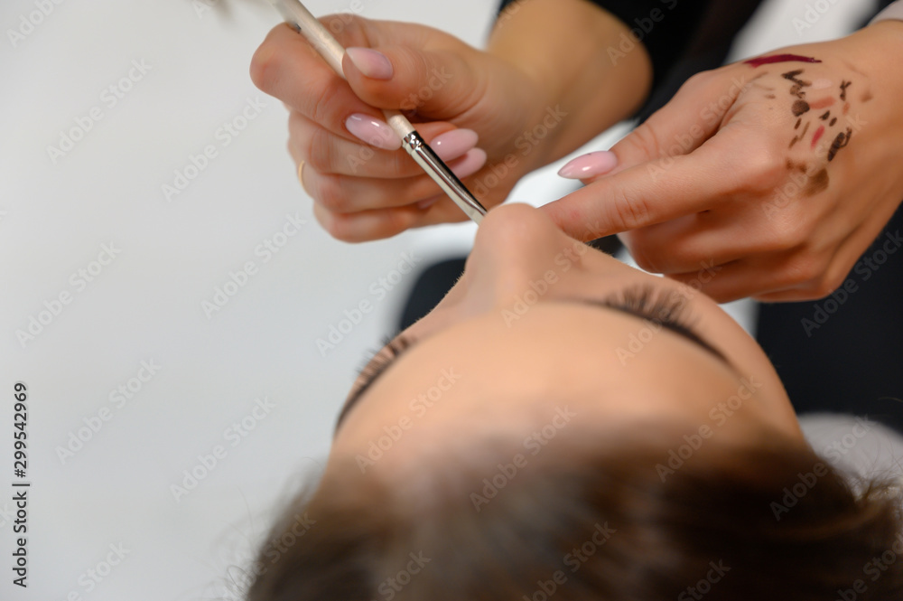 Studio photo of the work of a makeup artist by a hairdresser beautician. Creating beautiful makeup and hairstyles, rejuvenating the skin of the face. The professional is working with special tools. Studio photo of the work of a makeup artist by a hairdresser beautician. Creating beautiful makeup and hairstyles, rejuvenating the skin of the face. The professional is working with special tools.