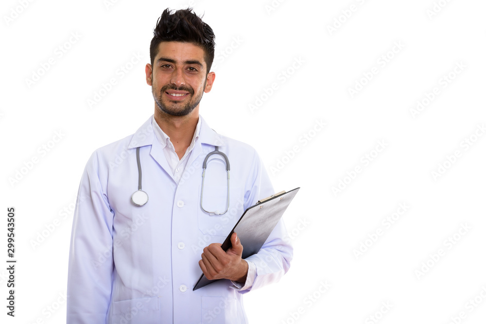 Portrait of young handsome bearded Persian man doctor holding clipboard Portrait of young handsome bearded Persian man doctor holding clipboard