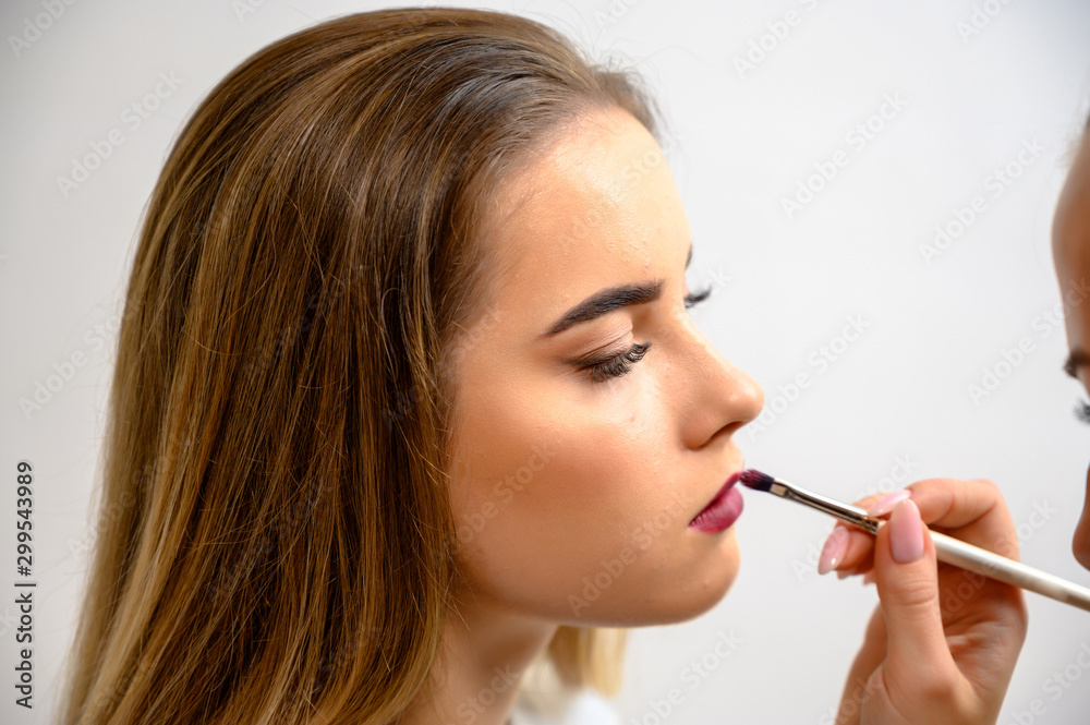 Studio photo of the work of a makeup artist by a hairdresser beautician. Creating beautiful makeup and hairstyles, rejuvenating the skin of the face. The professional is working with special tools. Studio photo of the work of a makeup artist by a hairdresser beautician. Creating beautiful makeup and hairstyles, rejuvenating the skin of the face. The professional is working with special tools.