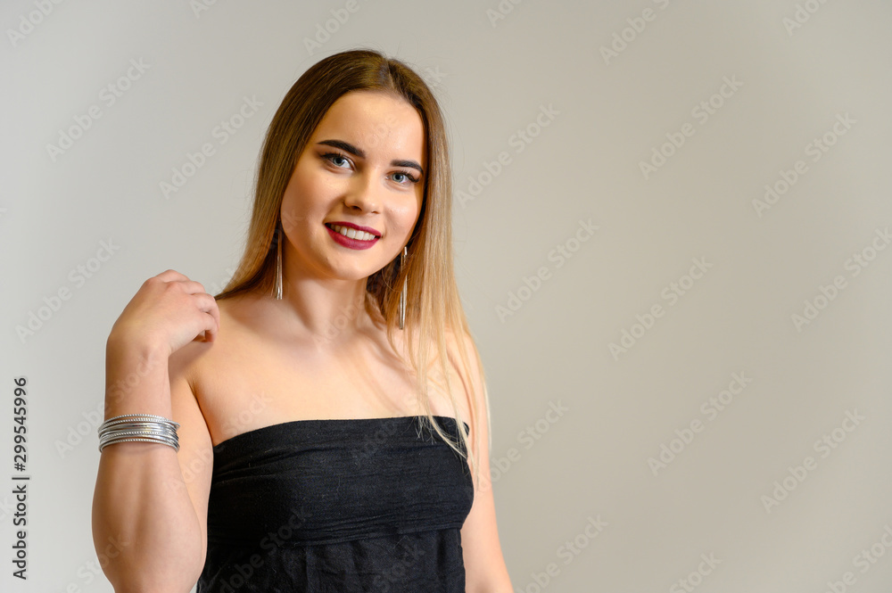 Studio portrait of a beautiful girl with long beautiful hair and excellent make-up on a gray background in different poses. She smiles. Studio portrait of a beautiful girl with long beautiful hair and excellent make-up on a gray background in different poses. She smiles.