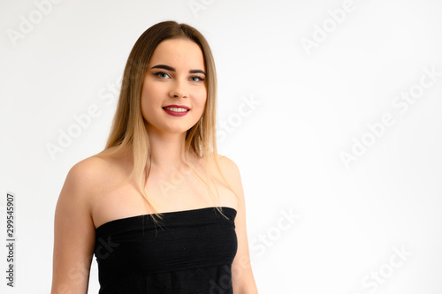 Studio portrait of a beautiful girl with long beautiful hair and excellent make-up on a gray background in different poses. She smiles.