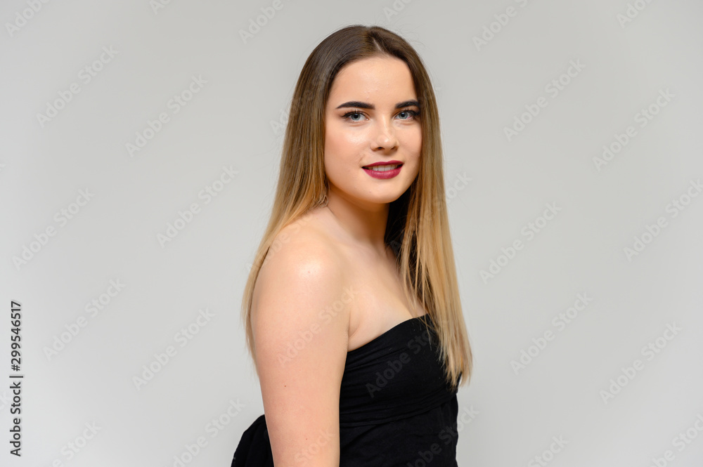 Studio portrait of a beautiful girl with long beautiful hair and excellent make-up on a gray background in different poses. She smiles. Studio portrait of a beautiful girl with long beautiful hair and excellent make-up on a gray background in different poses. She smiles.