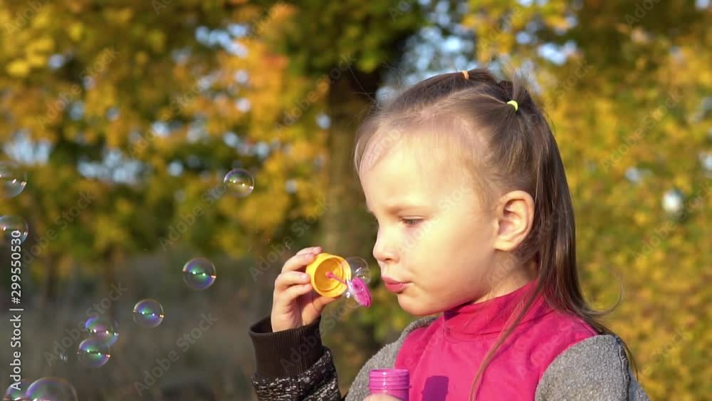 Beautiful little girl child blows soap bubbles. Plays in the autumn park. Slow motion. Beautiful little girl child blows soap bubbles. Plays in the autumn park. Slow motion.