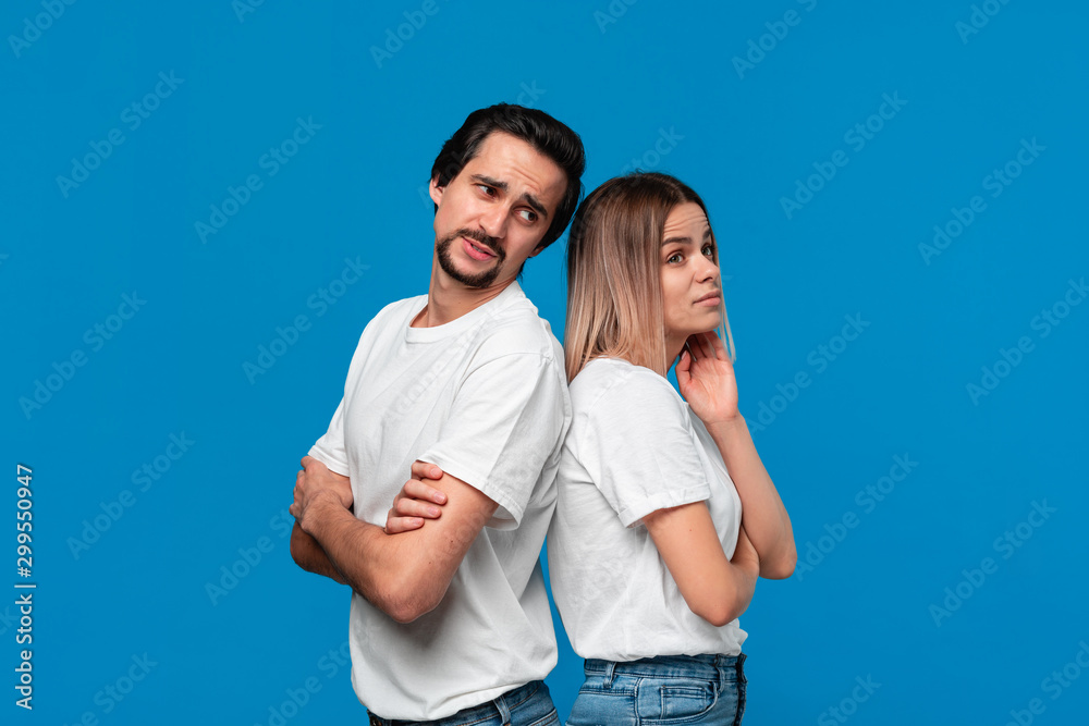 Couple of a young blond woman and brunet bearded man with mustaches in white t-shirts and blue jeans disputing about important issues. Couple of a young blond woman and brunet bearded man with mustaches in white t-shirts and blue jeans disputing about important issues.