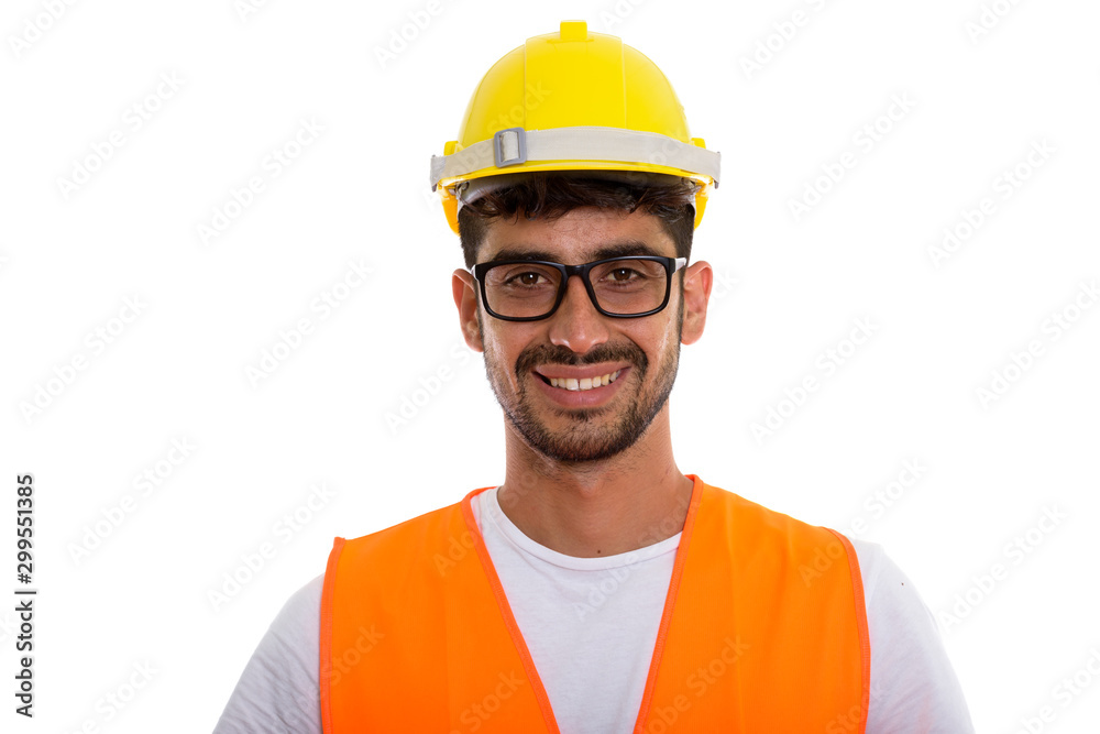 Studio shot of young happy Persian man construction worker smili Studio shot of young happy Persian man construction worker smili