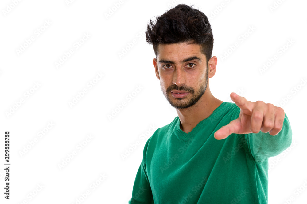 Studio shot of young Persian man pointing at camera Studio shot of young Persian man pointing at camera