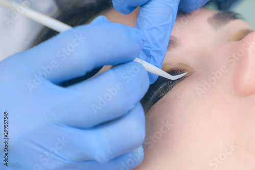 Beautician bending lashes with needle into curlers  lift eyelashes laminaton procedure in beauty salon for young woman. Cosmetologist making lash lifting in cosmetology clinic  hands closeup.