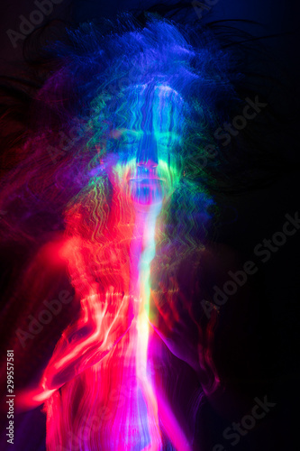 Conceptual avant-garde portrait of a beautiful young girl covered with multicolored lines applied by a light brush. Art style creative photo. Advertising, fashion and commercial design. © Алексей Торбеев