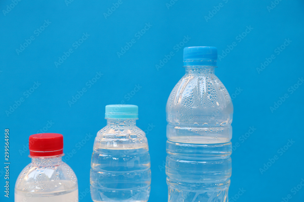 Closeup of three bottles of drinking water with blue background Closeup of three bottles of drinking water with blue background