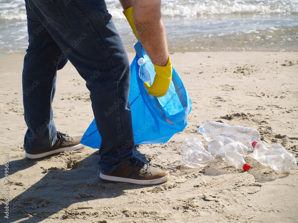 Man picking up a plastic bottle, save the environment, collecting trash Man picking up a plastic bottle, save the environment, collecting trash