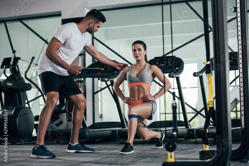 personal trainer holding clipboard while assisting of attractive sportswoman exercising with resistance band © LIGHTFIELD STUDIOS