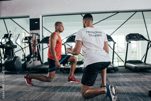 Slika na platnu back view of personal trainer instructing african american sportsman exercising