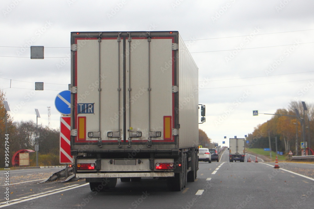 Europe Diesel white semi truck moveing on leftt lane autumn asphalt road, back view, transportation logistics