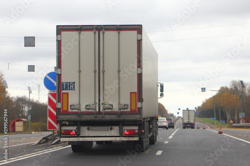 Europe Diesel white semi truck moveing on leftt lane autumn asphalt road, back view, transportation logistics