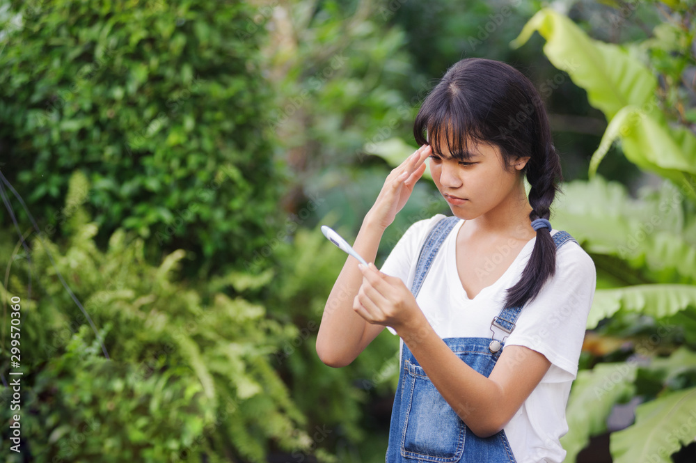 asian teenager woman with pigtail hairs in white shirt looking at thermometer and hands holding a digital thermometer in the garden asian teenager woman with pigtail hairs in white shirt looking at thermometer and hands holding a digital thermometer in the garden