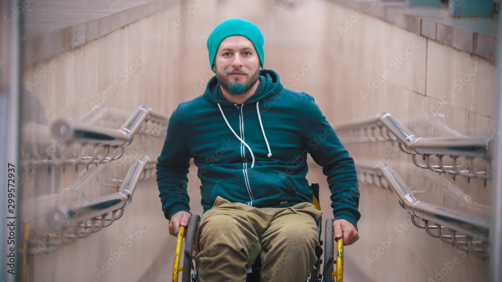 Disabled smiling man in wheelchair on the beginning of the ramp Disabled smiling man in wheelchair on the beginning of the ramp