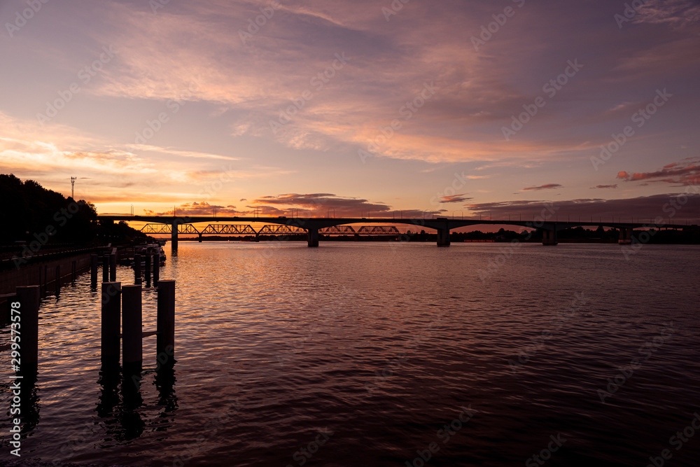 Russia, Golden Ring, Yaroslavl: Panorama view over Volga river water in the city center of the Russian town with colorful sunset, reflections and big bridges at the horizon - travel atmosphere