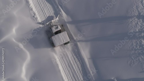 Aerial shot: View of mountain peaks covered in deep snow, while ascending with a snow cat during a day of cat skiing. Epic snowy mountains with Snow groomer. transfer by snowcat freeride
