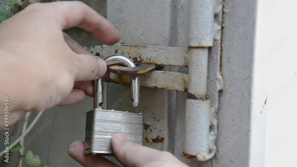 Close up house rusty front gate locks steel padlock by hand of man Close up house rusty front gate locks steel padlock by hand of man