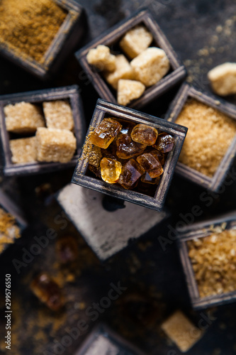 Flat lay composition with different types of sugar on dark background.