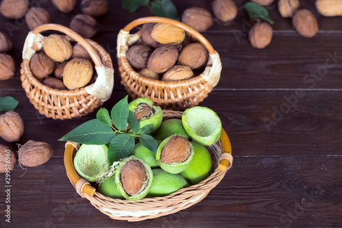 walnuts in wicker baskets closeup. background with a crop of walnuts. walnuts in green shell and the leaves of the walnut tree.