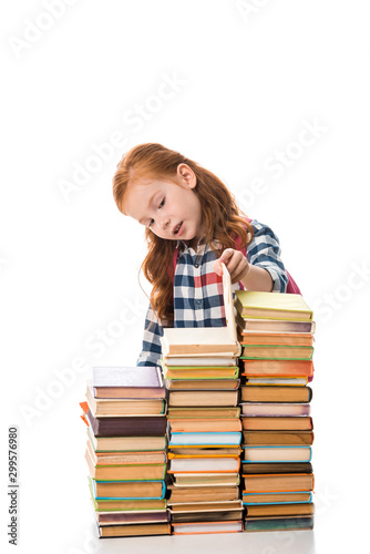 cute redhead pupil looking at books isolated on white