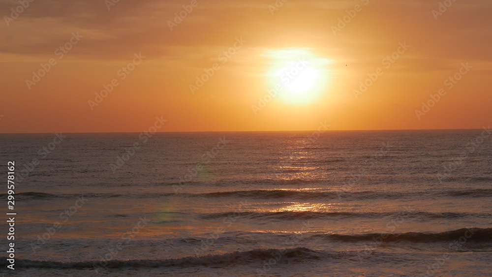 Sunrise over the sea. The sun is showing and coloring the sky in  red and golden yellow. Bright path to the shore.