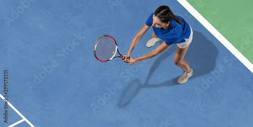 Young caucasian brunette woman in blue shirt playing tennis at the court. Hits ball with racket, outdoors. Youth, flexibility, power, energy. Copyspace. Top view. Motion, action, healthy lifestyle. © master1305