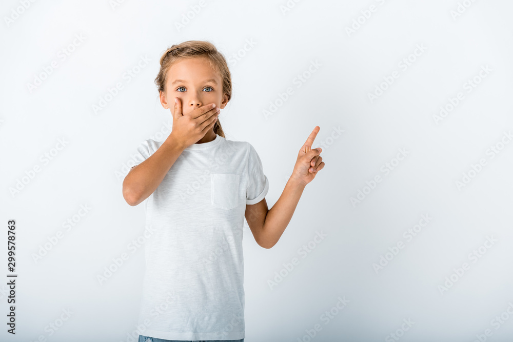 shocked kid covering face while looking at camera and pointing with finger on white shocked kid covering face while looking at camera and pointing with finger on white