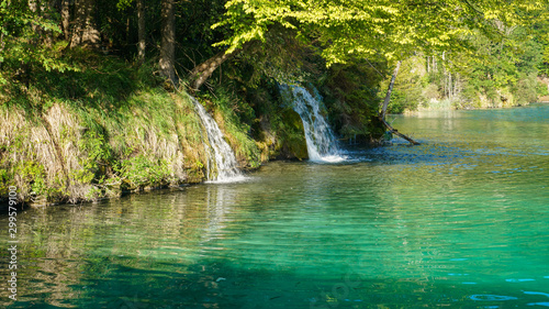 Water falls directly from the forest onto the turquoise surface of the lake