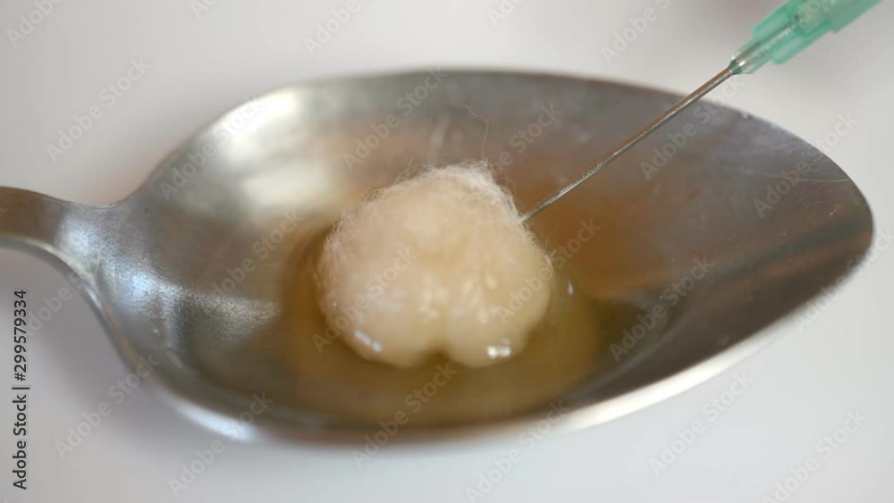 The heroin addict concept, Dirty heroin on steel spoon is filtered with cotton on a needle in a glass syringe on white background hd stock footage