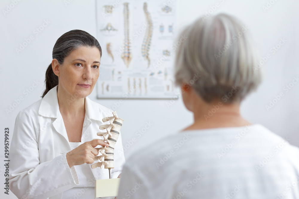 Ταπετσαρία Aging and back pain concept: doctor of orthopedics showing her senior patient a slipped disk on a backbone model