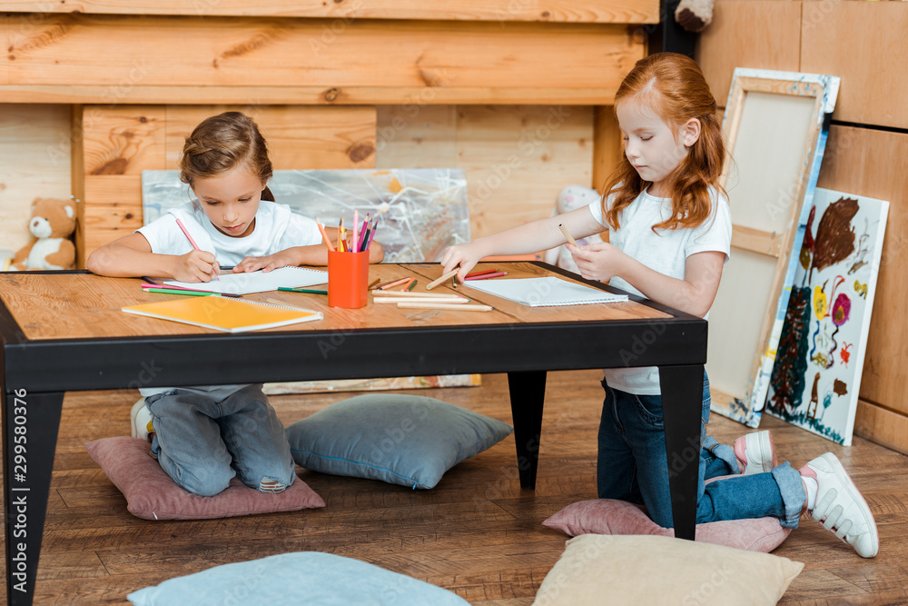 cute kids drawing on papers while sitting on pillows cute kids drawing on papers while sitting on pillows