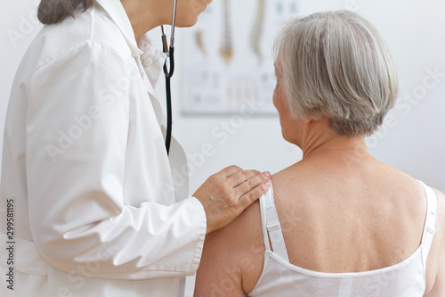 Fotografie Health care concept: female doctor auscultating the heart of a senior patient with a stethoscope