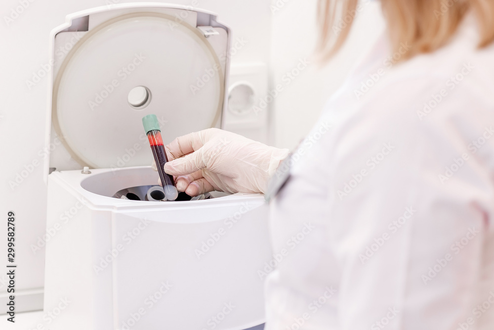 Female cosmetologist uses medical plasma centrifuge for plasma lifting procedure in cosmetology clinic. Young nurse in laboratories starts on device for mixing process of separation plasma from blood Female cosmetologist uses medical plasma centrifuge for plasma lifting procedure in cosmetology clinic. Young nurse in laboratories starts on device for mixing process of separation plasma from blood