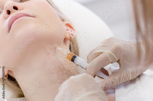 Close-up of a cosmetologist's hand doing injections for plasma restoration and necklift to a young woman client of a cosmetology cabinet. Concept of a young neck and anti-aging skin treatments