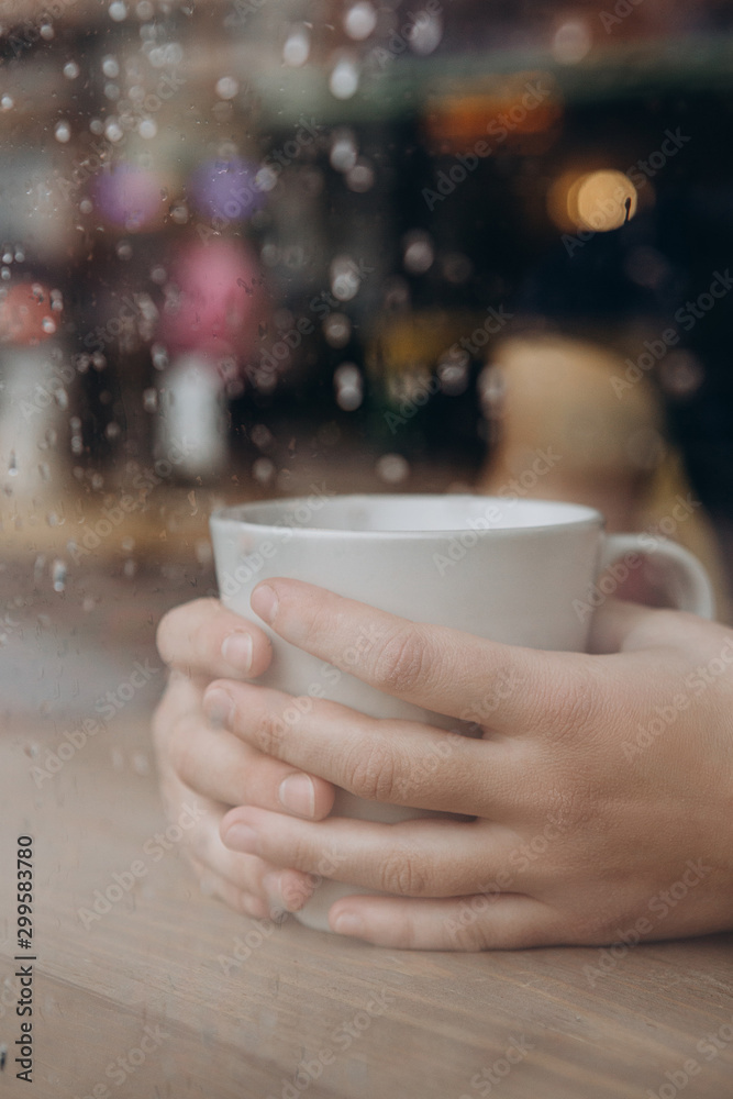 Woman hand holding the cup of coffee or tea on rainy day window background in vintage color tone, copy space Woman hand holding the cup of coffee or tea on rainy day window background in vintage color tone, copy space