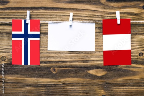 Hanging flags of Bouvet Islands and Peru attached to rope with clothes pins with copy space on white note paper on wooden background.Diplomatic relations between countries. photo