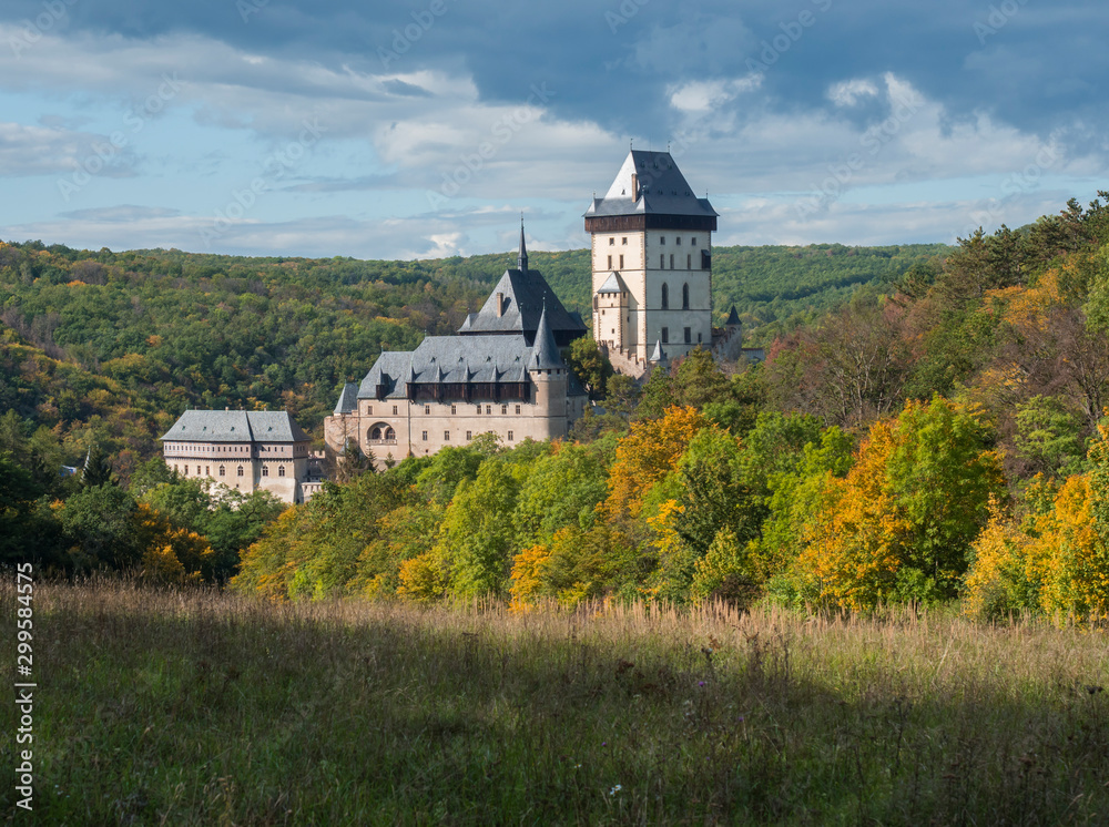 Obraz premium Karlstejn gothic state castle near Prague, the most famous castle in Czech Republic with grass meadow and autumn colored trees and forest. Blue sky clouds background. Located near Prague.