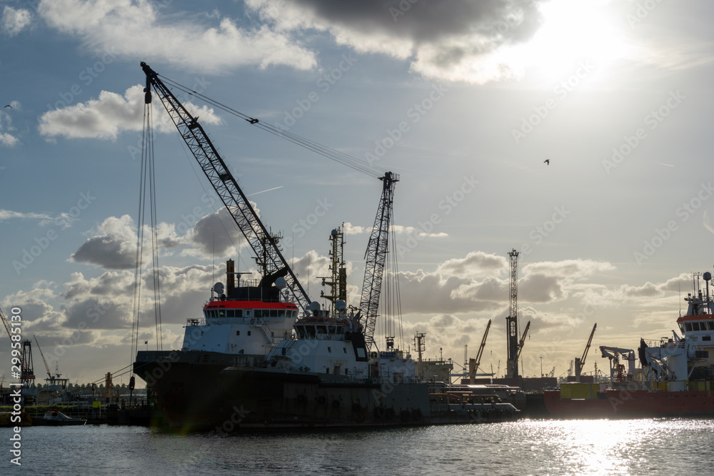 Setting sun in the port of Rotterdam, the Netherlands, Europe. Ships and cranes.